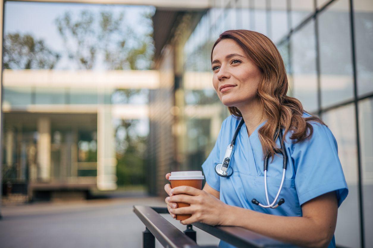 A nurse dressed in scrubs enjoys a cup of coffee, preparing for her day at the hospital.